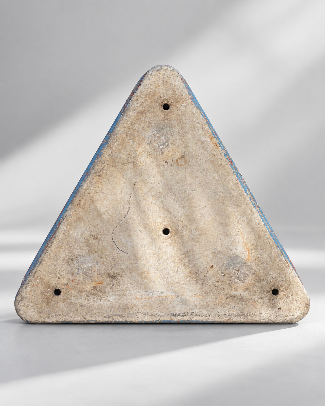 Underside of triangular garden planter with drainage holes and worn finish