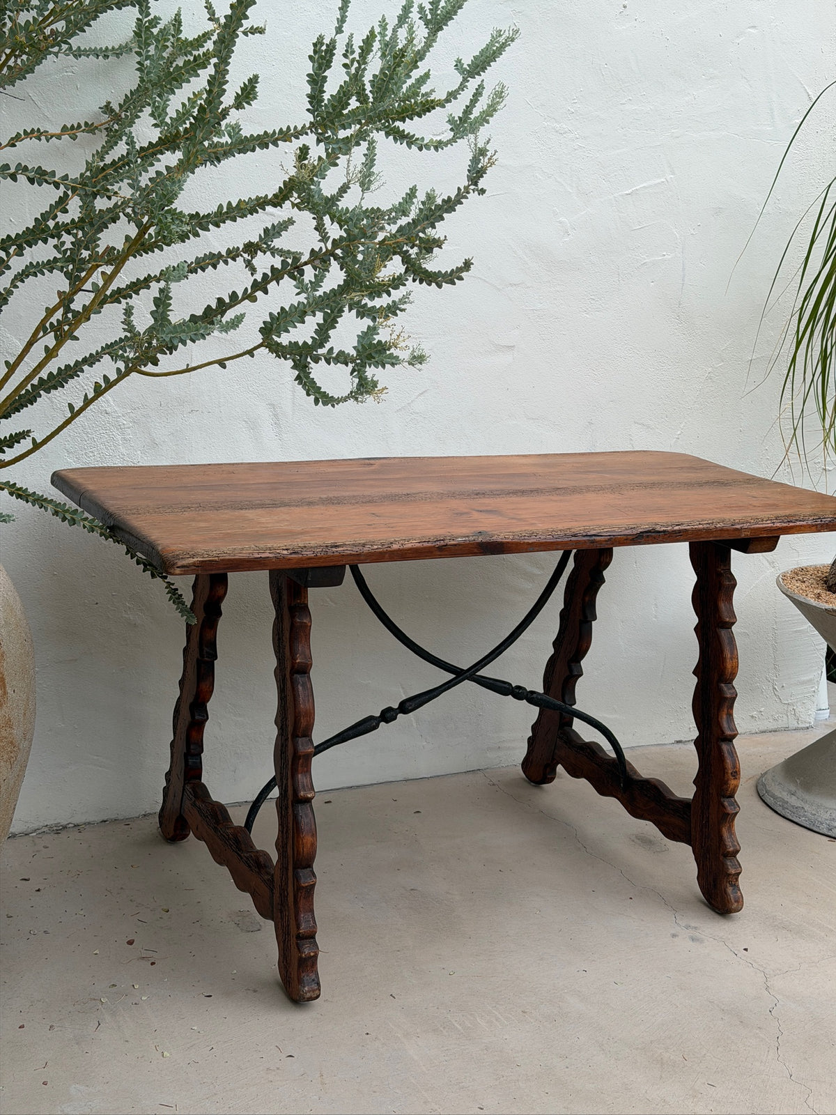 Angled view of Spanish Revival console table with wood top and iron stretchers