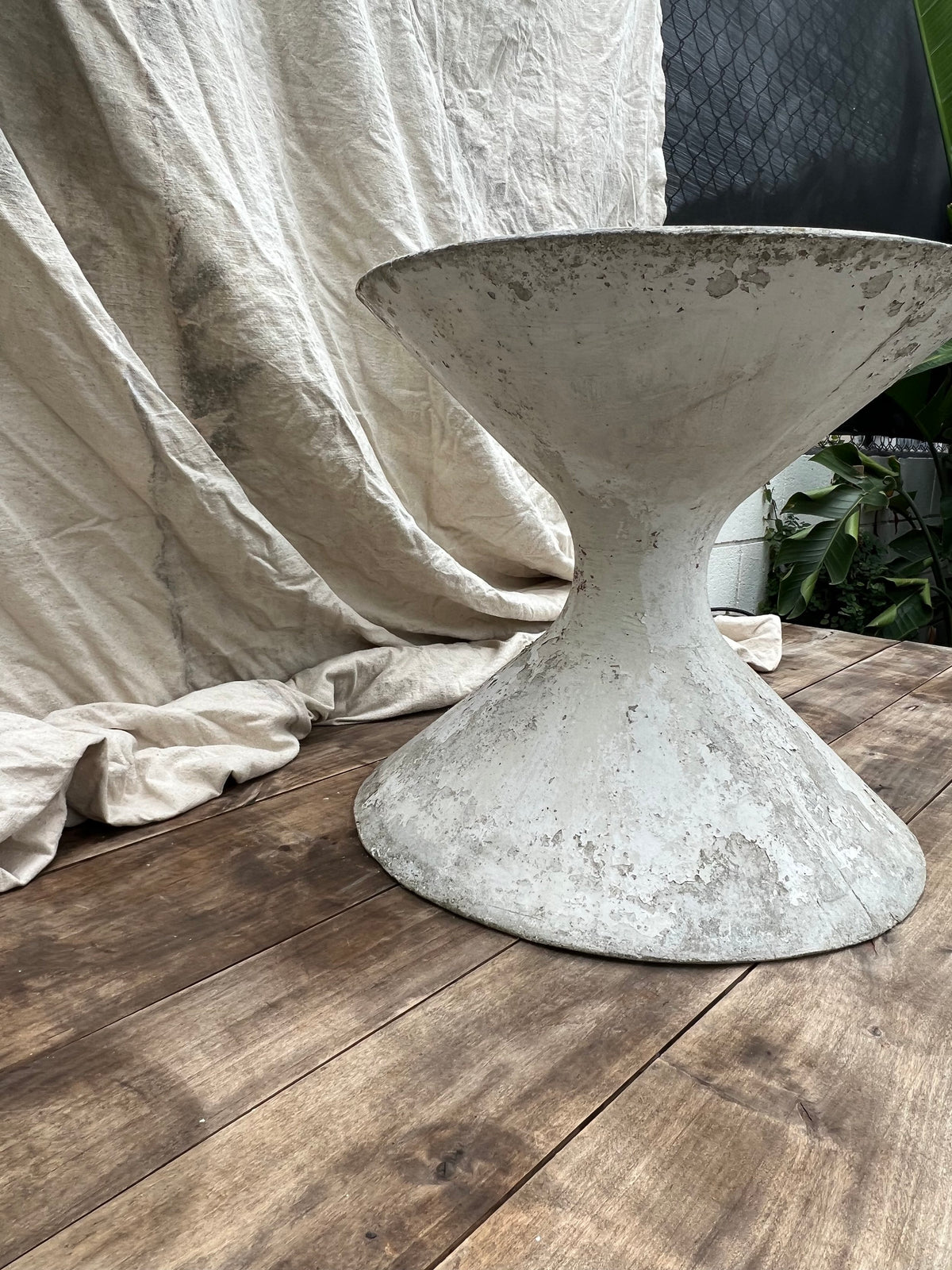 A vintage Willy Guhl hourglass-shaped planter made of fibrous cement, showing signs of wear and patina.