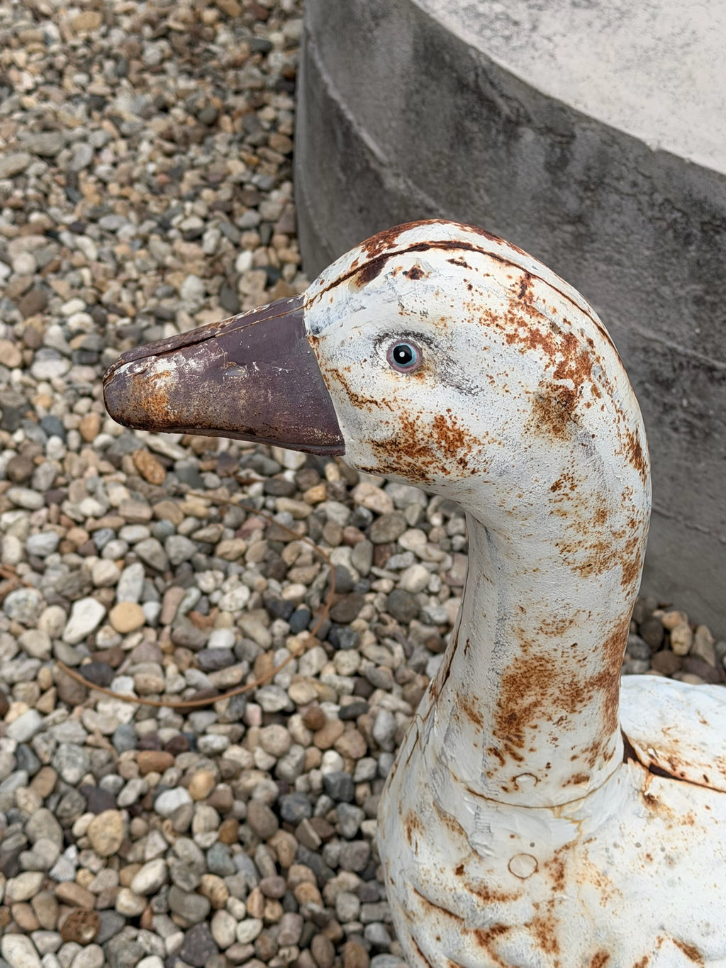 Close-up of weathered white paint on cast metal goose garden statue