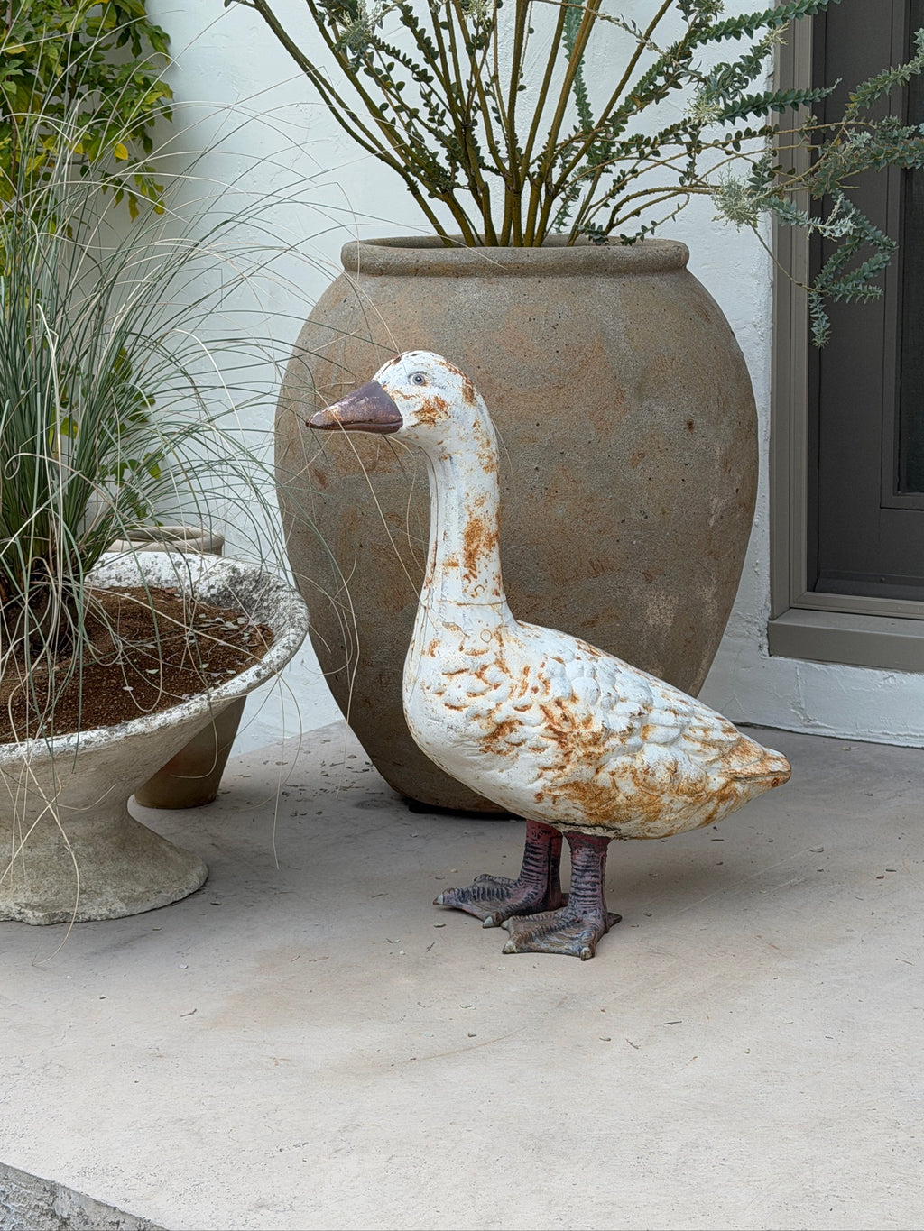Side view of cast metal goose garden statue with distressed white paint