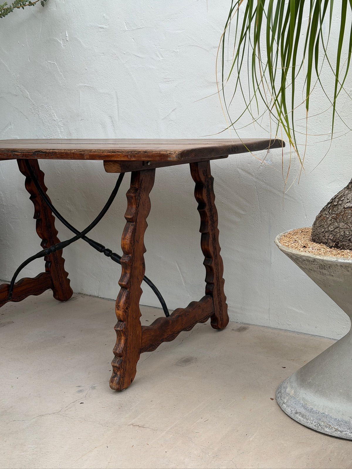 Angled view of Spanish Revival console table with wood top and iron stretchers