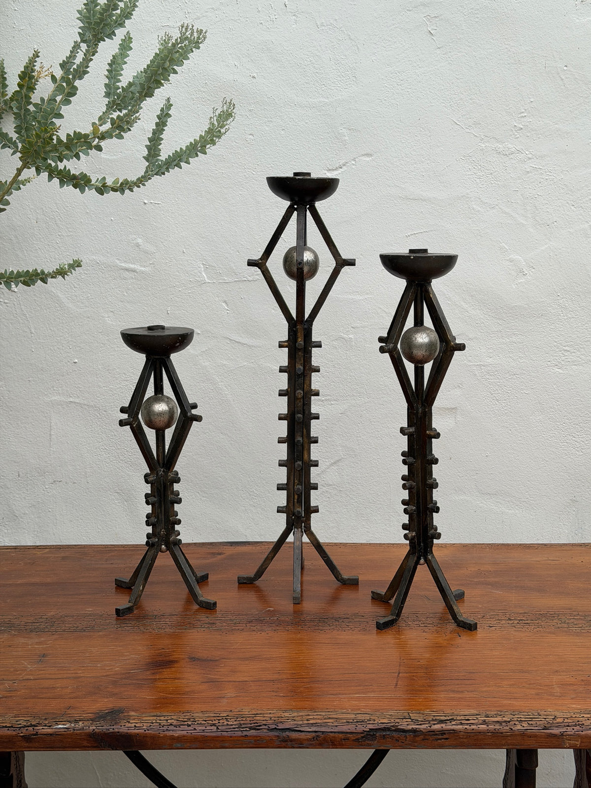 Three vintage wrought iron floor candlesticks with graduated heights and orb accents