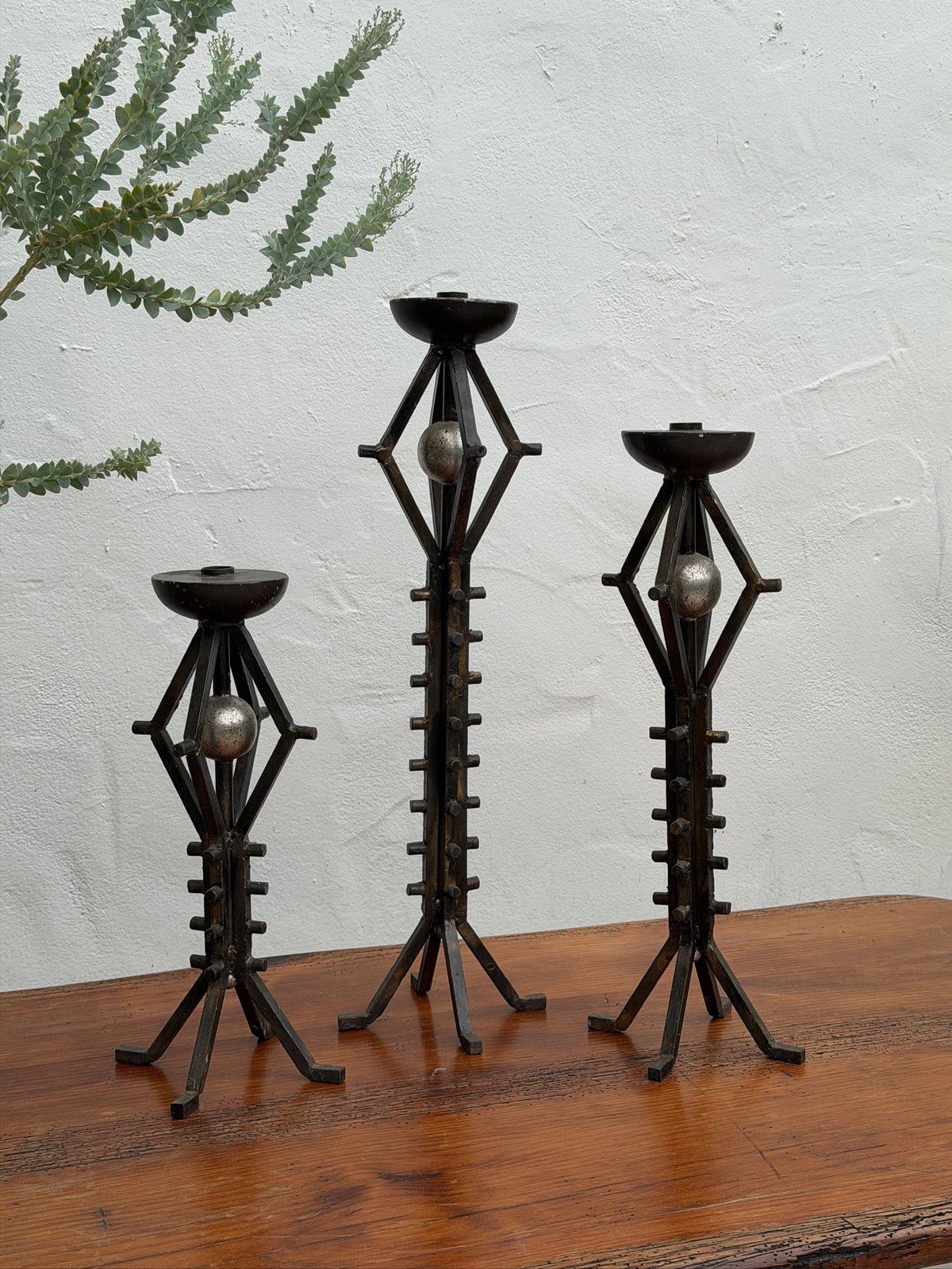 Graduated set of three wrought iron floor candlesticks with sculptural orb details