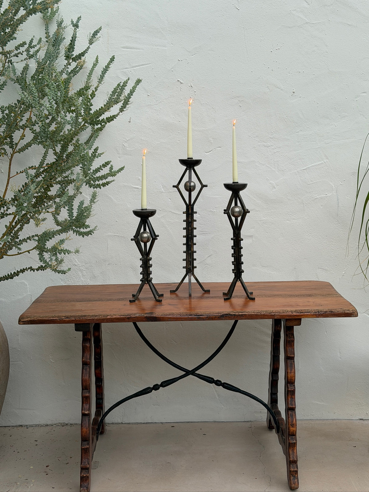 Graduated set of three wrought iron floor candlesticks with sculptural orb details