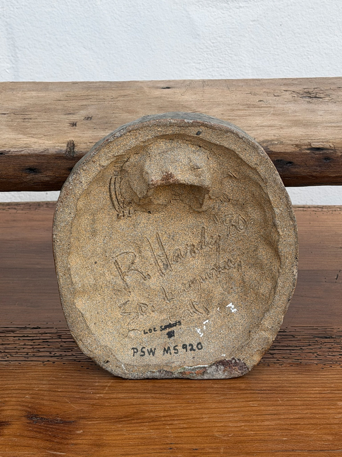 Reverse detail of sculptural face plaque with signed R. Hardy marking
