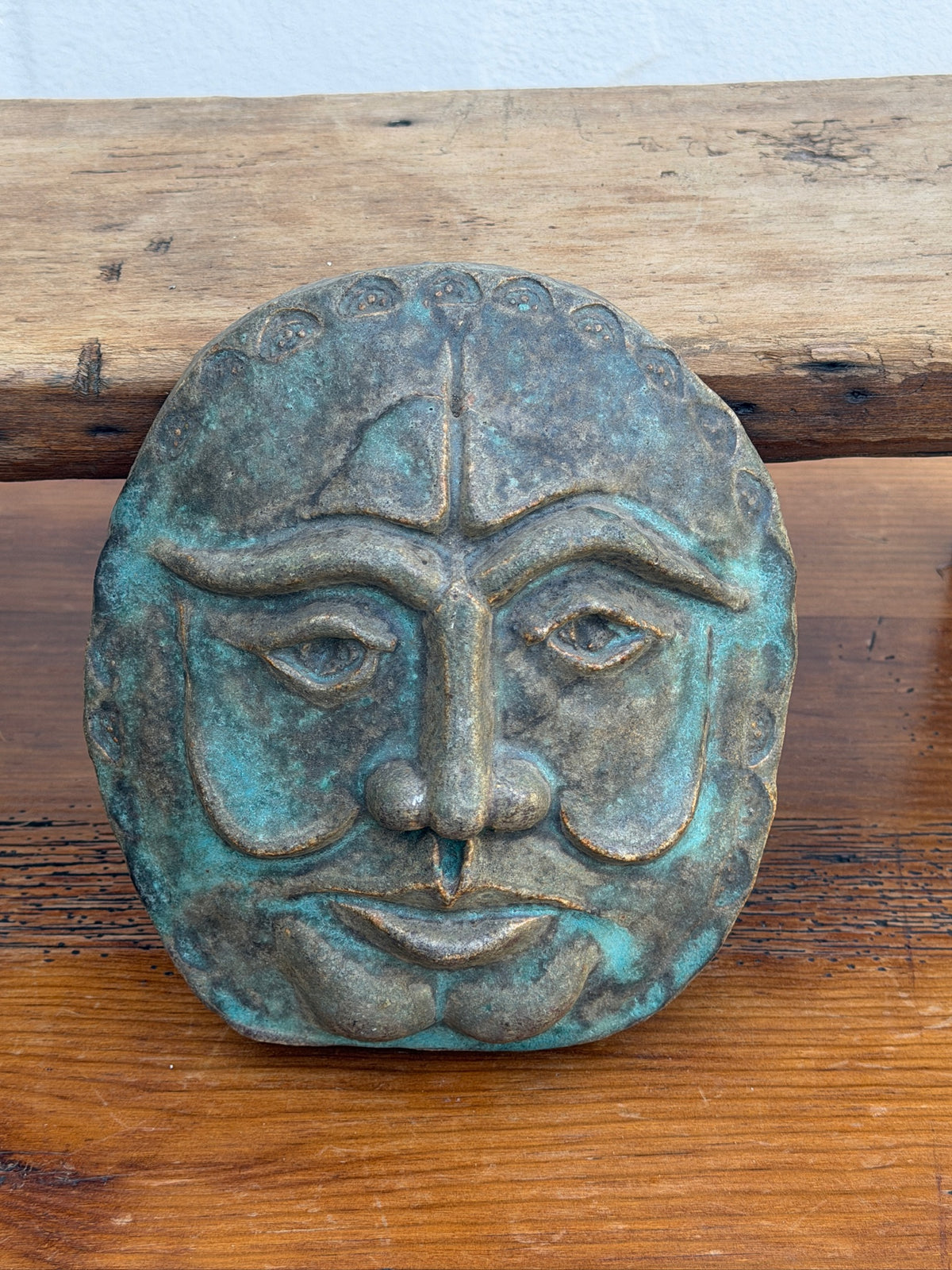 Detail of blue-green finish on sculptural face wall plaque
