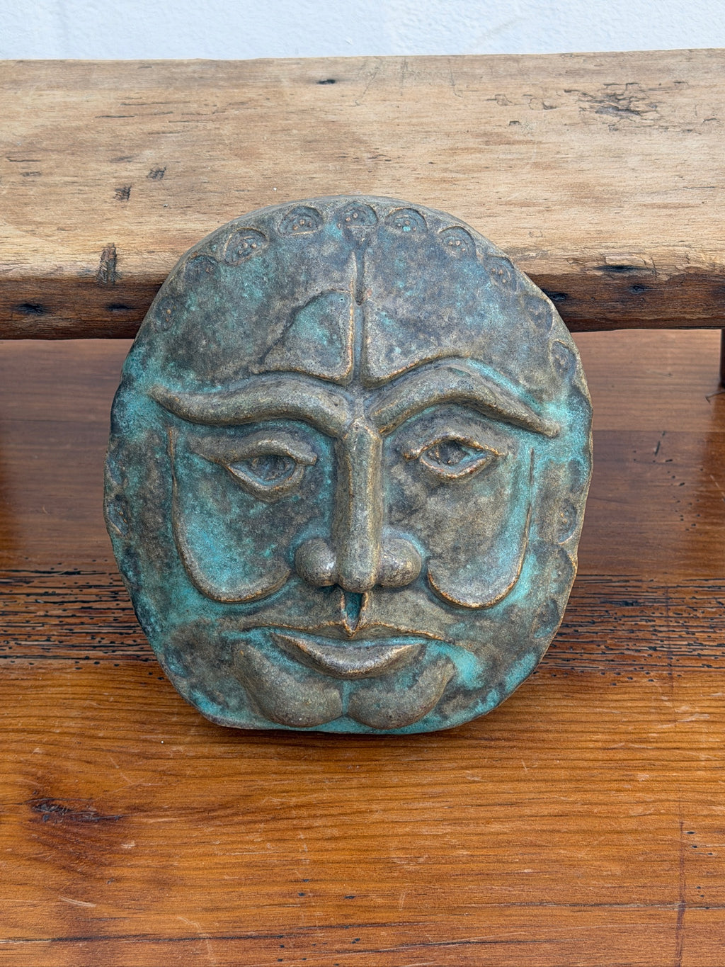 Close-up of face wall plaque with raised features and verdigris finish