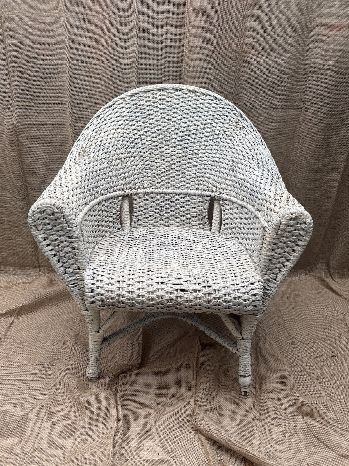 Vintage white wicker armchair with barrel-back design