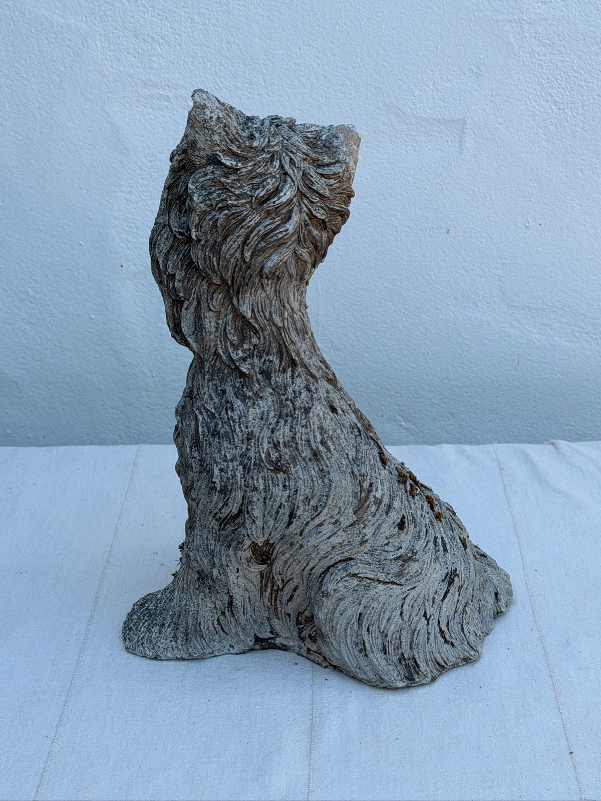 Side view of weathered terrier dog garden statue