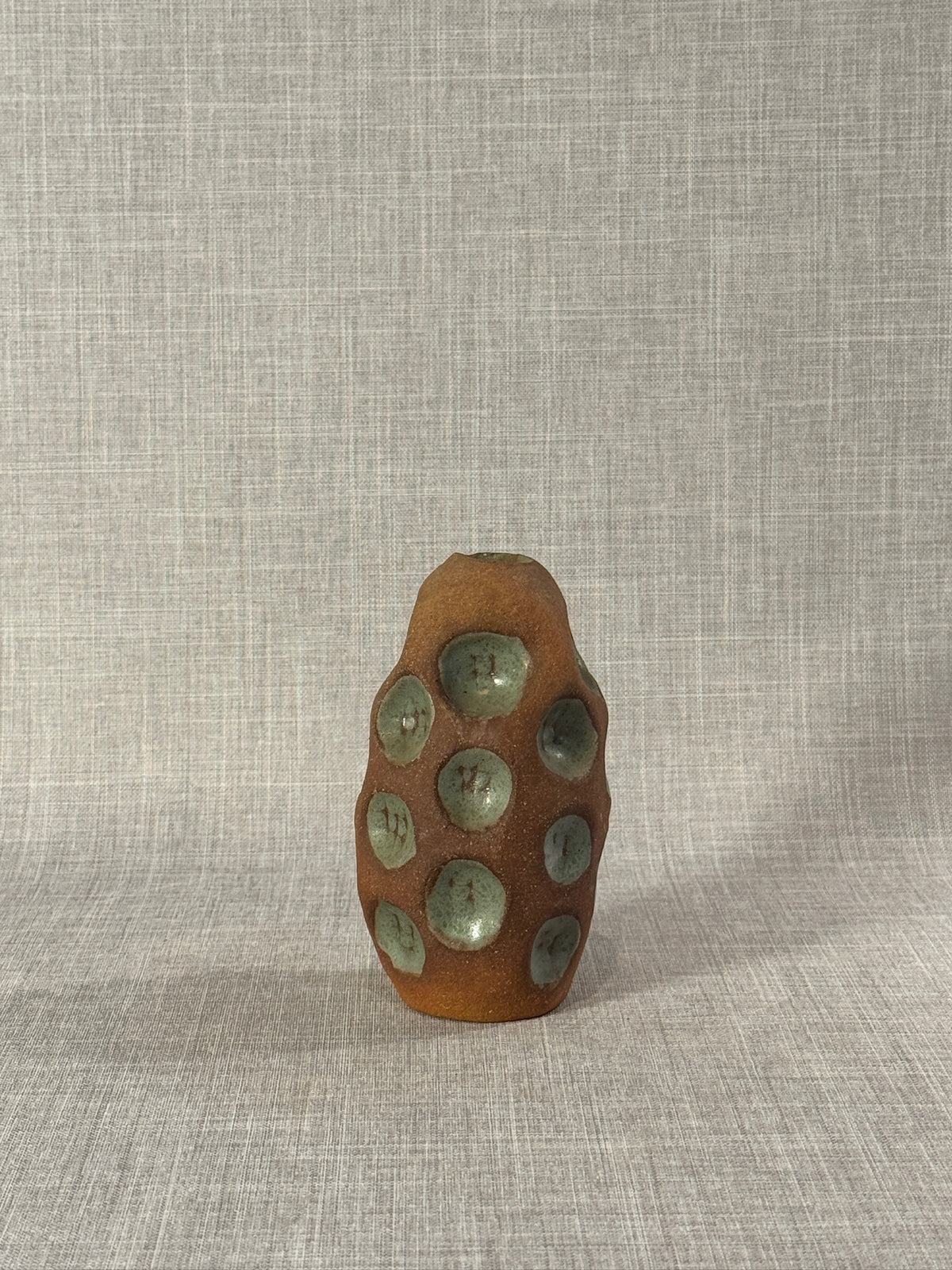 Handmade Terracotta Glazed Studio Pottery Bud Vase with Celadon Impressions on textured background, hommes + gardens estudio.