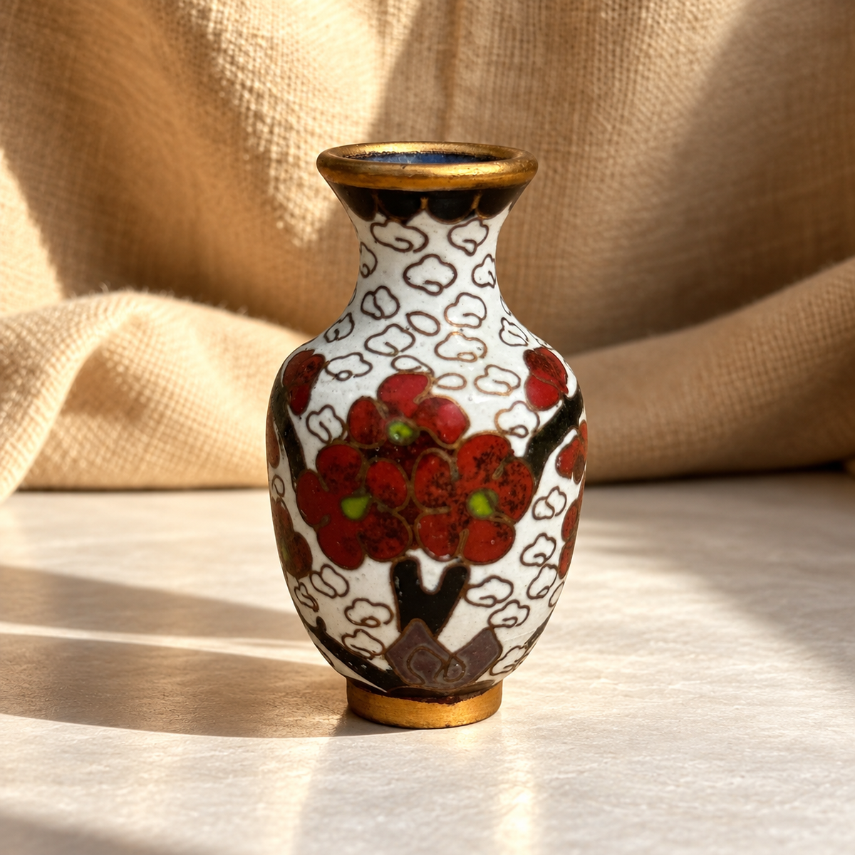 Small Chinese cloisonné enamel bud vase with creamy white ground, red blossom motif, green details and brass-toned rim and base, a petite mid-century decorative vessel — Hommes and Gardens, Vases + Vessels Collection, Objects + Curiosities Collection, Home Decor, Interior Designer, Home Design, Luxury Design, Art, Furniture, Objects, Chinese Design, Asian Decor, Cloisonné Enamel, Decorative Arts, Collectible Objects, Best Gifts.
