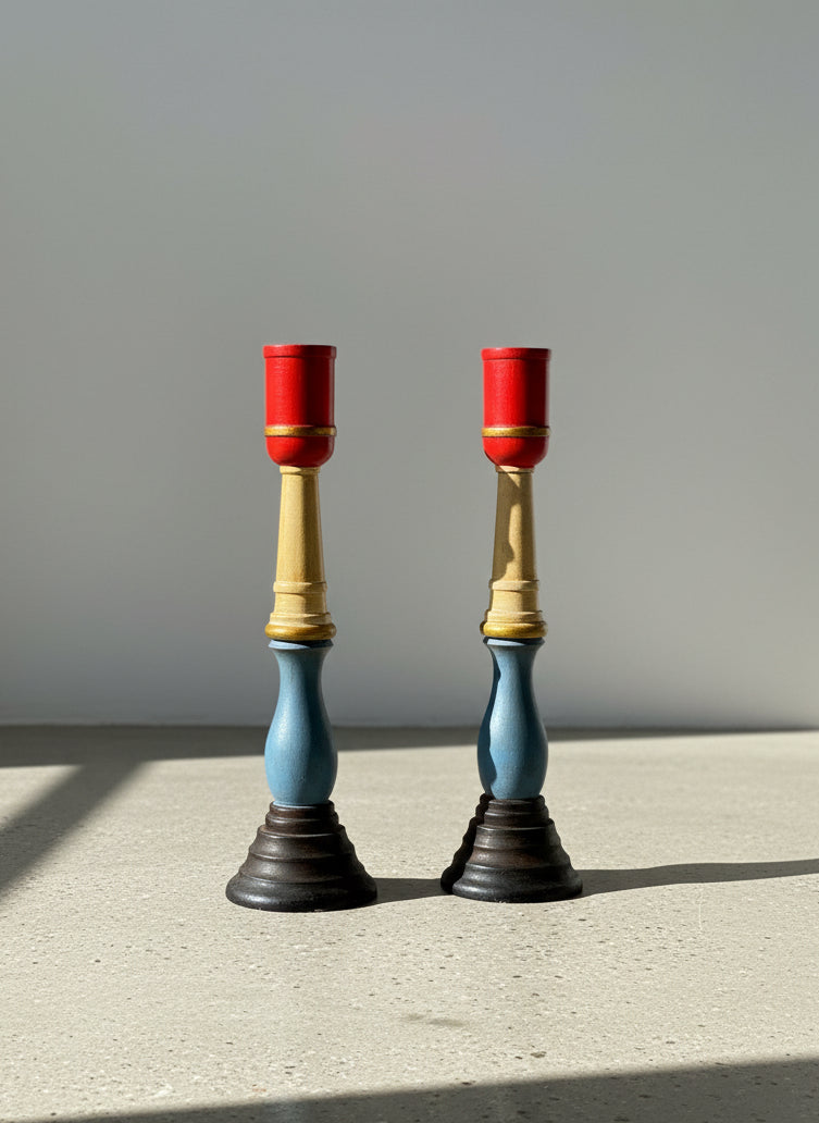 Two candle holders with red tops and blue and gold bodies on a textured gray background