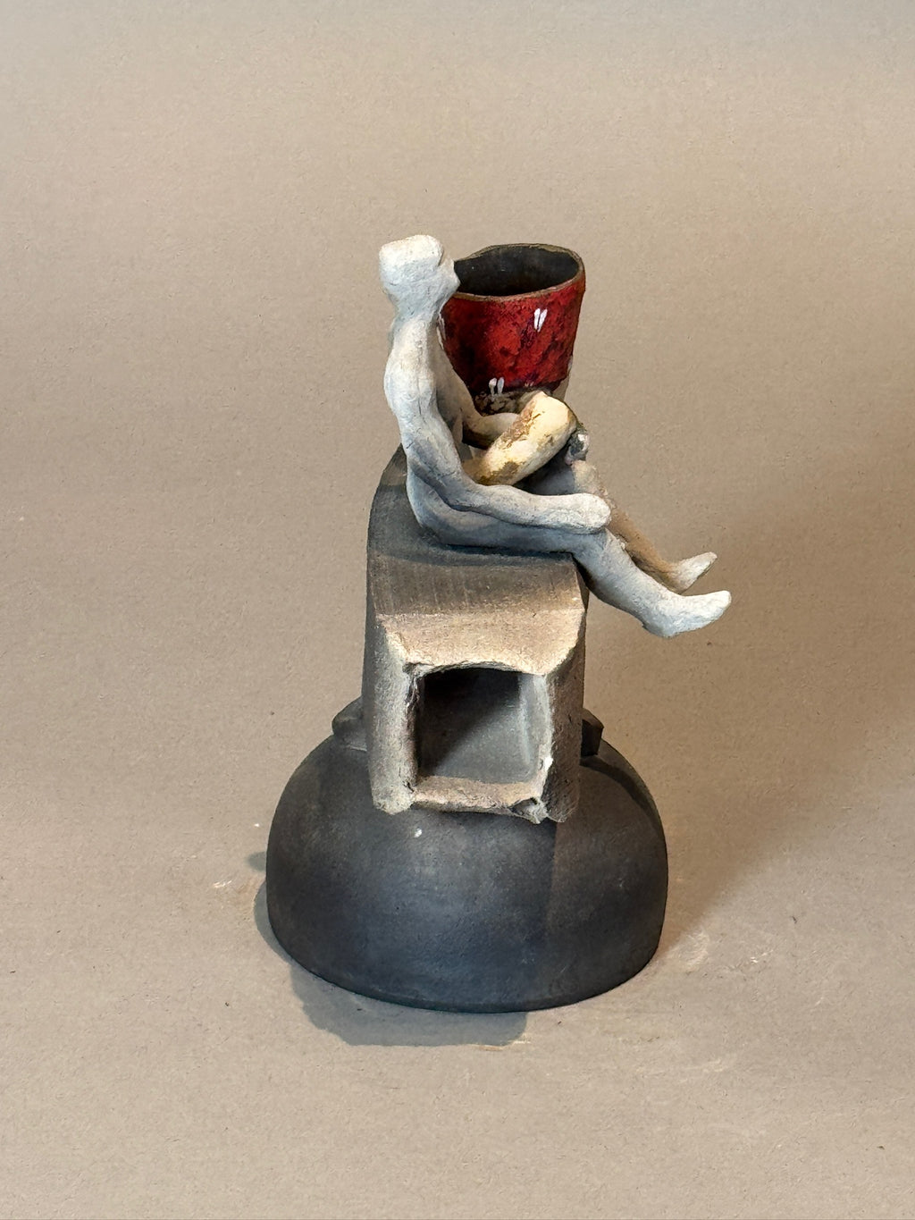 Abstract Modern Ceramic Sculpture – Human Figure with Red Vessel on geometric base, showcasing balance and artistic depth. hommes + gardens estudio.
