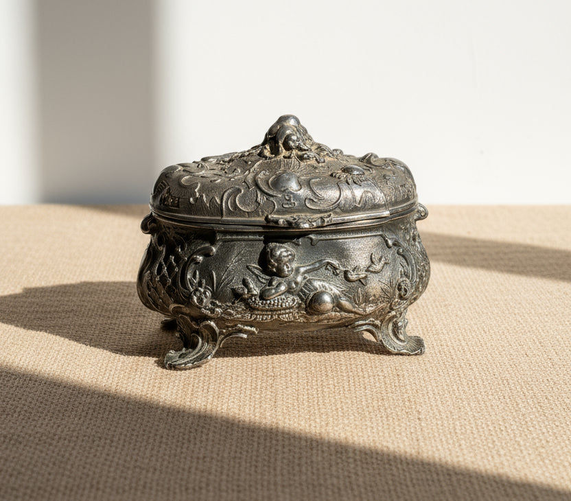 Antique 19th-century French metal jewelry box with intricate cherub and bird motifs, an ornate decorative object reflecting classic French craftsmanship — Hommes and Gardens, Decorative Collection, Home Decor, Landscape Architect, Interior Designer, Outdoor Living, Outdoor Decorations, Home Design, Luxury Design, Art, Furniture, Objects, Best Gifts, Nature, Backyard, Yard.