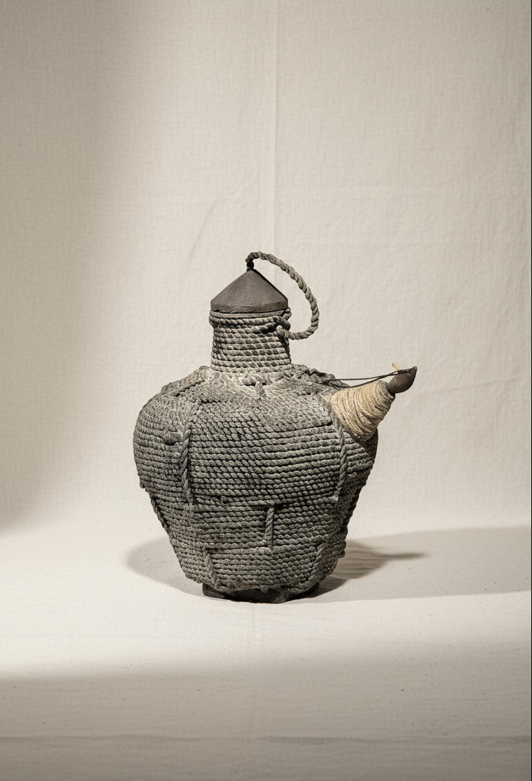 Antique Southeast Asian Kendi water pot crafted from wood and rattan in black and brown tones, a ceremonial vessel symbolizing regional artistry and cultural heritage — Hommes and Gardens, Home Decor Collection, Outdoor Decorations, Landscape Architect, Interior Designer, Outdoor Living, Home Design, Luxury Design, Art, Furniture, Objects, Best Gifts, Nature, Backyard, Yard.