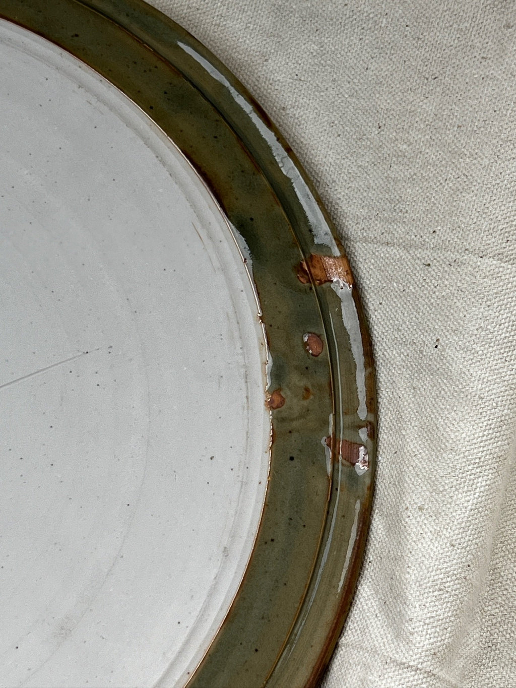 Close-up of signed vintage ceramic cake plate - earthy green, showcasing geometric details, rustic charm, hommes + gardens estudio.