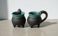 Artist-signed Sandi Pierantozzi ceramic mugs with textured sea urchin design, teal glaze interiors, and sculpted tentacle handles, a collectible handcrafted pottery set — Hommes and Gardens, Decorative Collection, Home Decor, Landscape Architect, Interior Designer, Outdoor Living, Outdoor Decorations, Home Design, Luxury Design, Art, Furniture, Objects, Best Gifts, Nature, Backyard, Yard.
