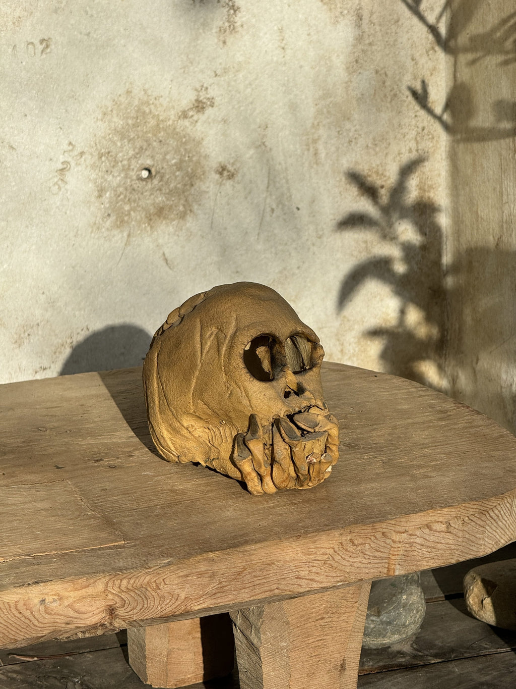 Ceramic skull candle holder with clasped hands design and open base for candle placement, a striking handcrafted décor piece — Hommes and Gardens, home decor, outdoor decorations, home design, luxury design, Landscape Architect, Interior Designer, Outdoor Living, Art, Furniture, Objects, Best Gifts, Nature, Backyard, Yard.
