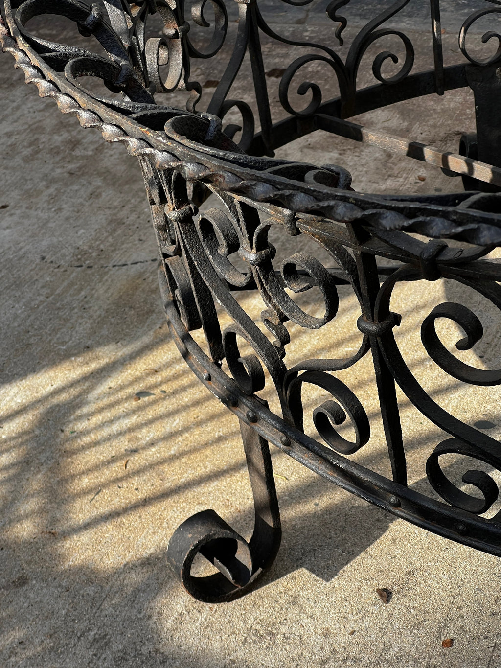 Close-up of Victorian Oval Wrought Iron Plant Holder showcasing intricate scrollwork and dark patina. hommes + gardens estudio