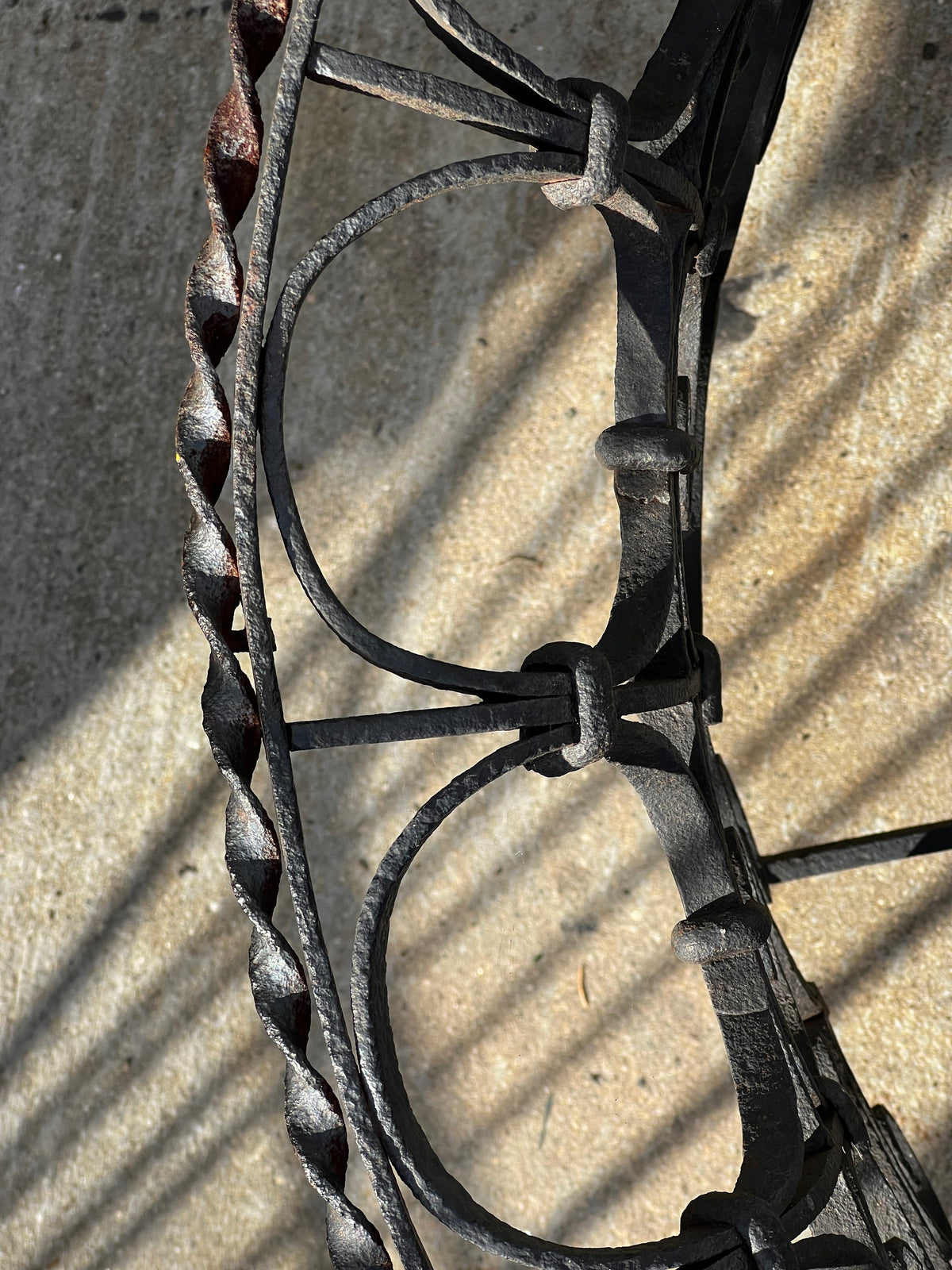 Close-up of Victorian Oval Wrought Iron Plant Holder showcasing intricate scrollwork and textured surfaces. hommes + gardens estudio.