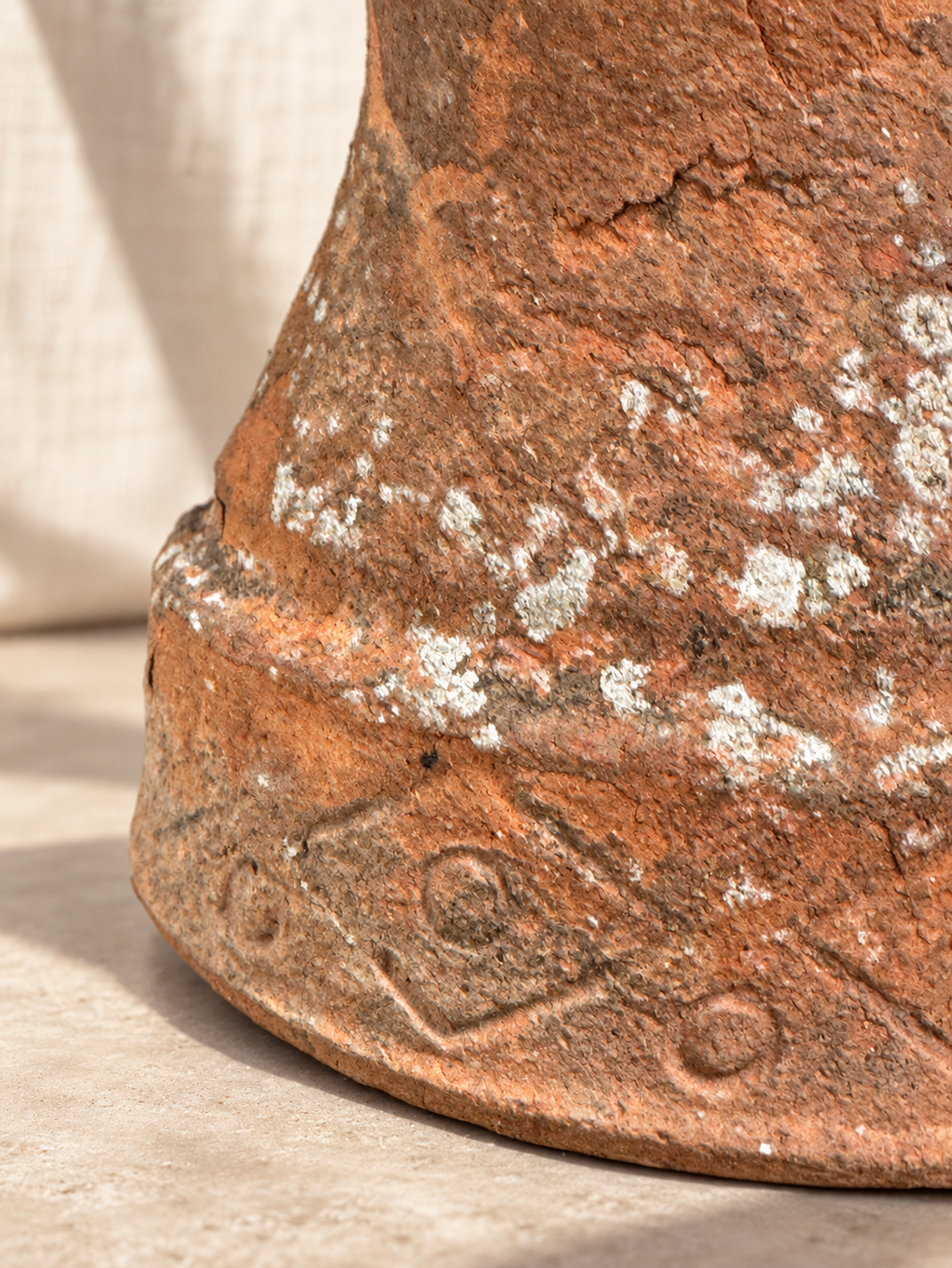 Weathered terracotta planter with mineral and lichen deposits