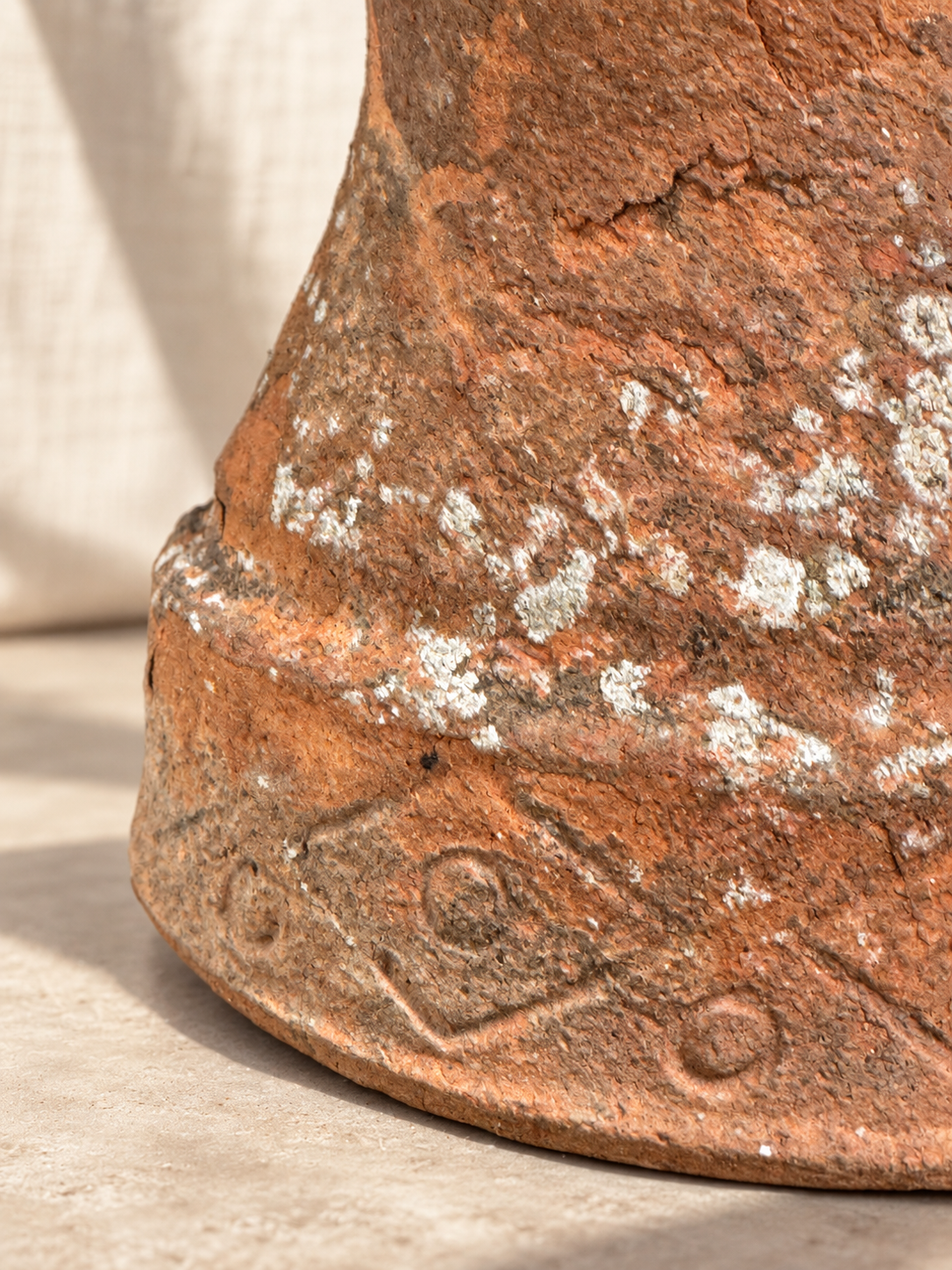 Weathered terracotta planter with mineral and lichen deposits